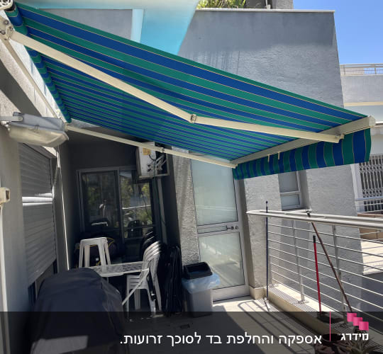 סוכך כחול ירוק מותקן על מרפסת
